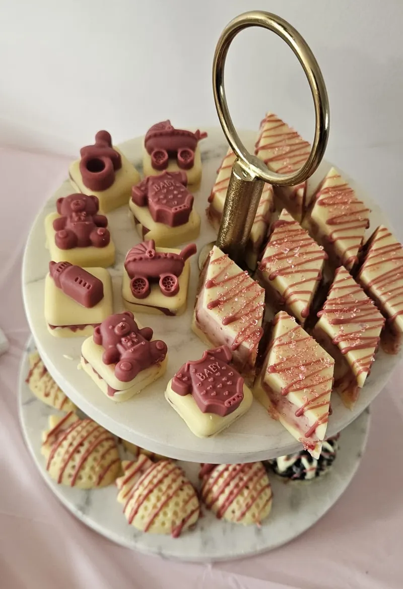 Etagère met gevulde blokken en reliëf-bonbons in de vorm van beertjes, kinderwagens en rompertjes